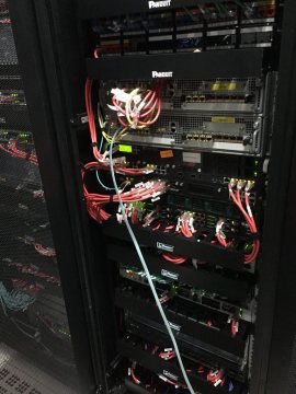 Rack jaringan terpasang dengan manajemen kabel berwarna pada patch panel.